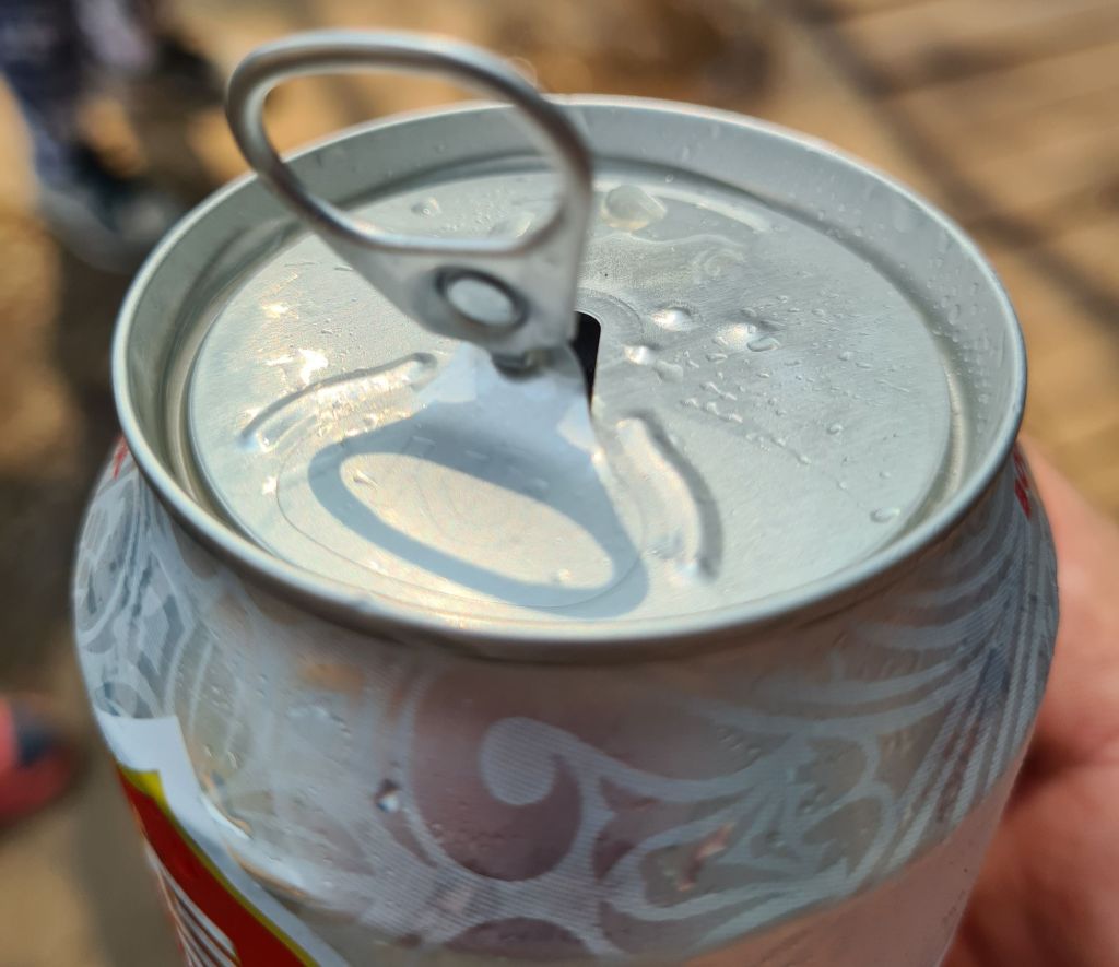 Close-up of a soda can with a tab and condensation on the surface.