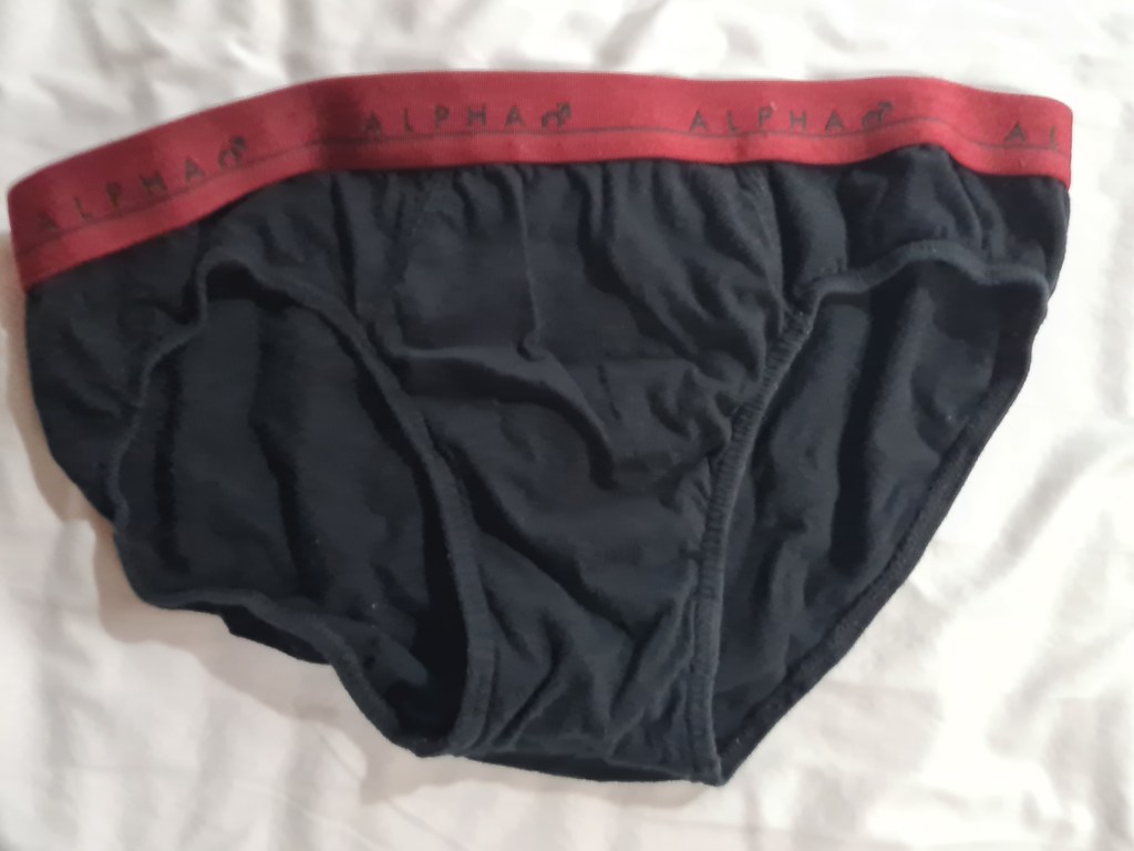Black men's briefs with a red waistband labeled 'ALPHA' on a white background.